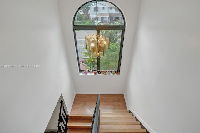 stairway with a notable chandelier and hardwood / wood-style flooring