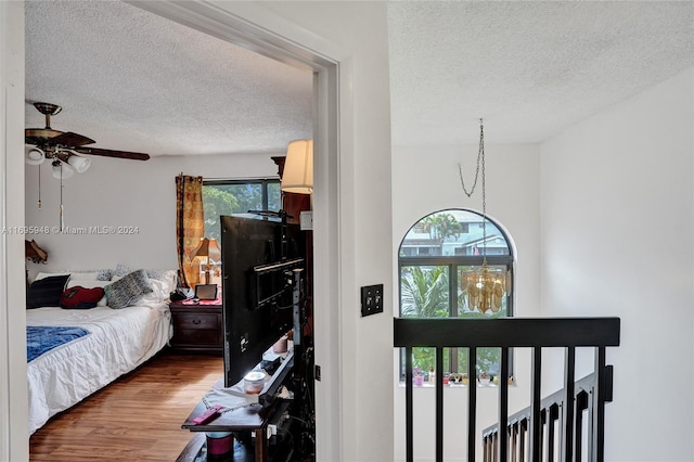 bedroom featuring multiple windows, ceiling fan, hardwood / wood-style floors, and a textured ceiling