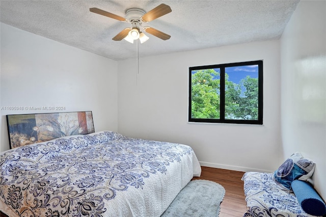 bedroom with hardwood / wood-style floors, a textured ceiling, and ceiling fan