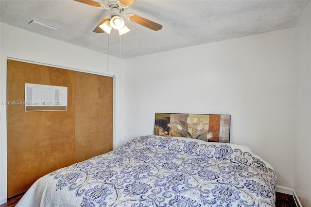 bedroom featuring ceiling fan, hardwood / wood-style floors, and a textured ceiling