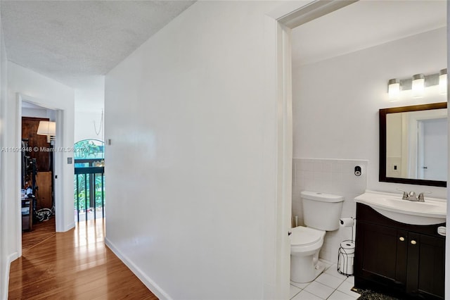 bathroom featuring vanity, a textured ceiling, hardwood / wood-style flooring, and toilet