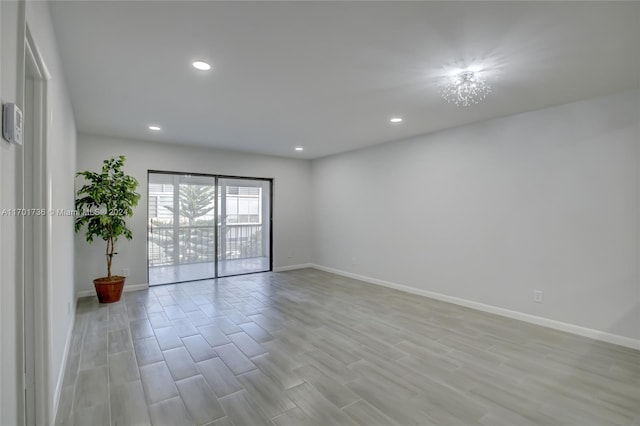 spare room featuring a chandelier and light wood-type flooring