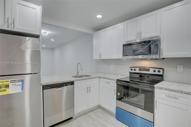 kitchen with sink, light stone counters, backsplash, white cabinets, and appliances with stainless steel finishes