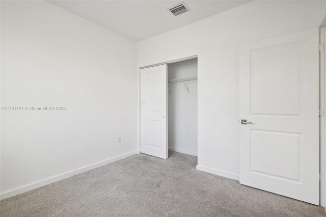 unfurnished bedroom featuring light carpet and a closet