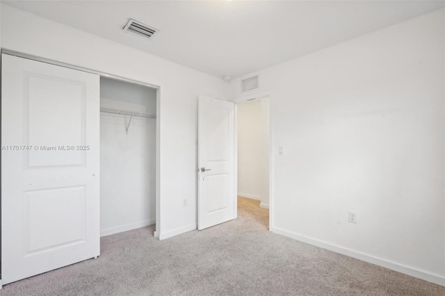 unfurnished bedroom with a closet and light colored carpet