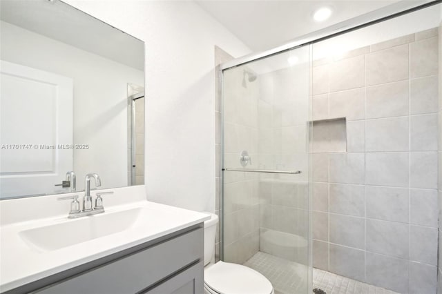 bathroom featuring toilet, vanity, and an enclosed shower