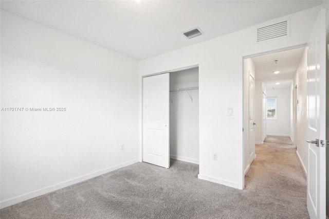 unfurnished bedroom with a closet and light colored carpet