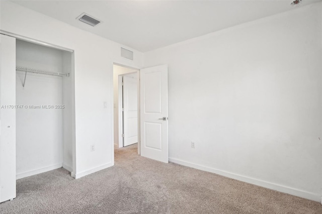 unfurnished bedroom featuring a closet and light colored carpet