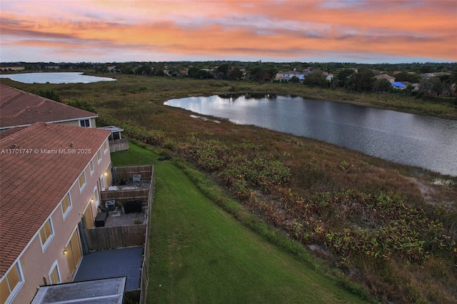 aerial view at dusk featuring a water view