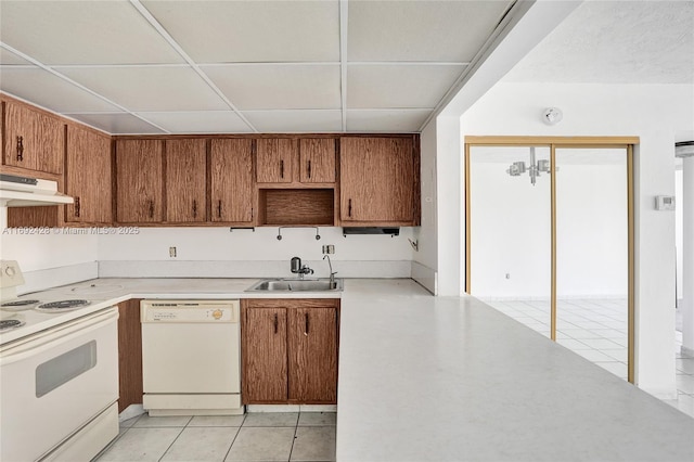 kitchen with brown cabinets, light countertops, a sink, white appliances, and under cabinet range hood