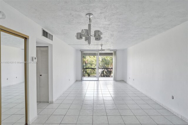 tiled spare room with ceiling fan with notable chandelier