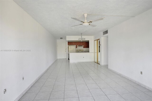 unfurnished living room featuring ceiling fan, light tile patterned flooring, and a textured ceiling