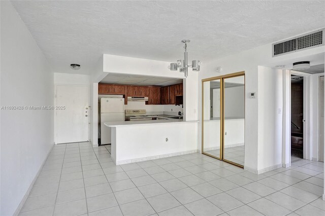 kitchen featuring white refrigerator, range with electric stovetop, kitchen peninsula, decorative light fixtures, and light tile patterned floors