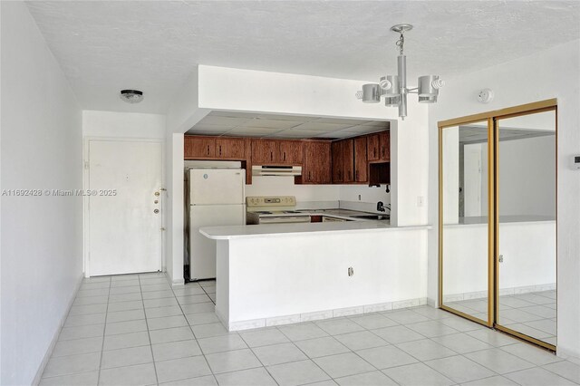 kitchen with sink, hanging light fixtures, kitchen peninsula, white appliances, and light tile patterned floors