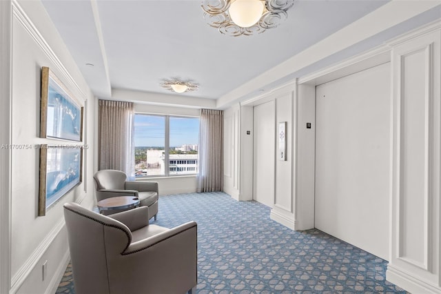 sitting room with elevator and carpet flooring