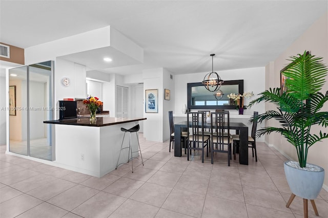 kitchen with hanging light fixtures, light tile patterned floors, a kitchen bar, an inviting chandelier, and white cabinets