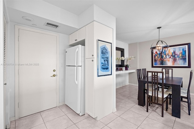 kitchen featuring a chandelier, pendant lighting, white fridge, light tile patterned floors, and white cabinets