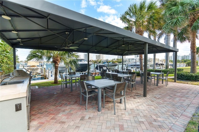 view of patio with a water view, exterior kitchen, and sink