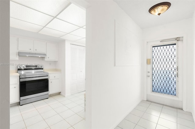 kitchen with stainless steel range with electric stovetop, a paneled ceiling, white cabinetry, and light tile patterned floors