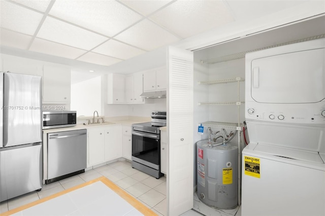 kitchen featuring stacked washing maching and dryer, electric water heater, stainless steel appliances, and white cabinetry