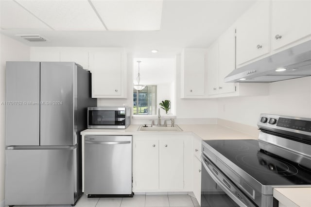 kitchen featuring a paneled ceiling, sink, light tile patterned flooring, white cabinetry, and stainless steel appliances