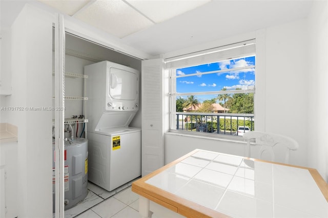 clothes washing area featuring electric water heater, light tile patterned flooring, and stacked washer / drying machine