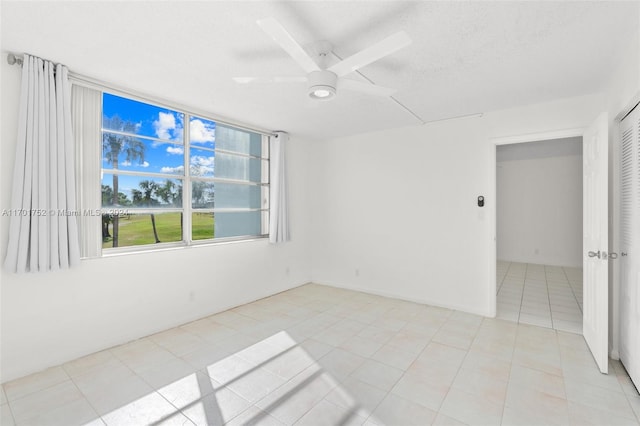 tiled empty room featuring ceiling fan and a textured ceiling