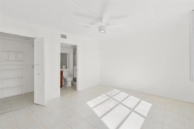 unfurnished bedroom with light tile patterned flooring, ensuite bath, a closet, and ceiling fan