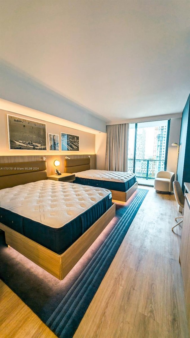 bedroom featuring hardwood / wood-style flooring, floor to ceiling windows, and access to exterior