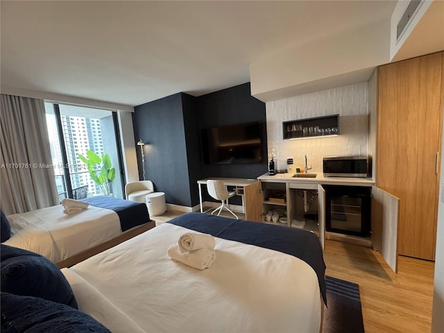 bedroom featuring sink, wine cooler, and light hardwood / wood-style flooring