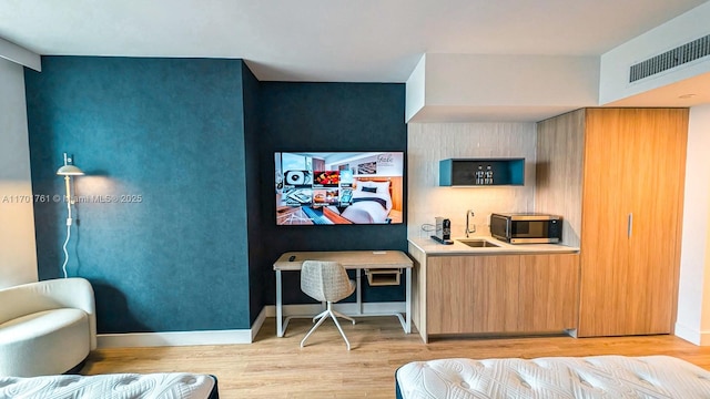 interior space with backsplash, sink, and light hardwood / wood-style flooring