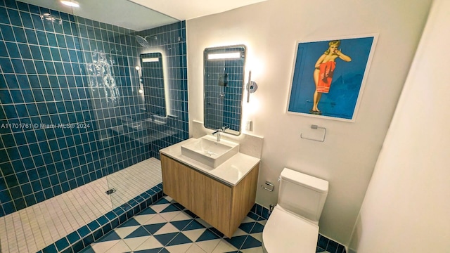 bathroom with tile patterned floors, vanity, toilet, and tiled shower