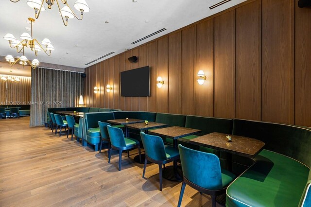 interior space with wooden walls, a chandelier, and light hardwood / wood-style flooring