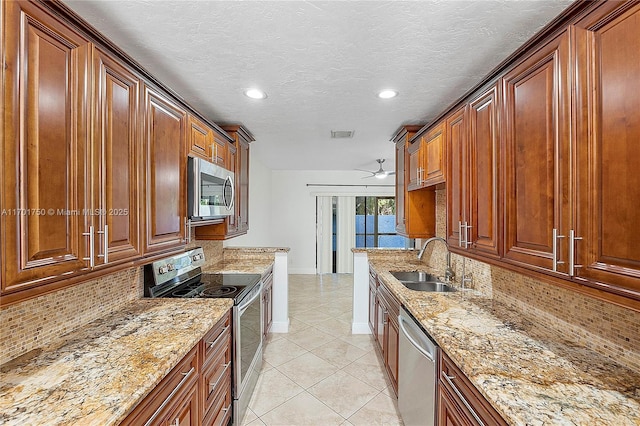 kitchen with light stone countertops, appliances with stainless steel finishes, decorative backsplash, a textured ceiling, and sink