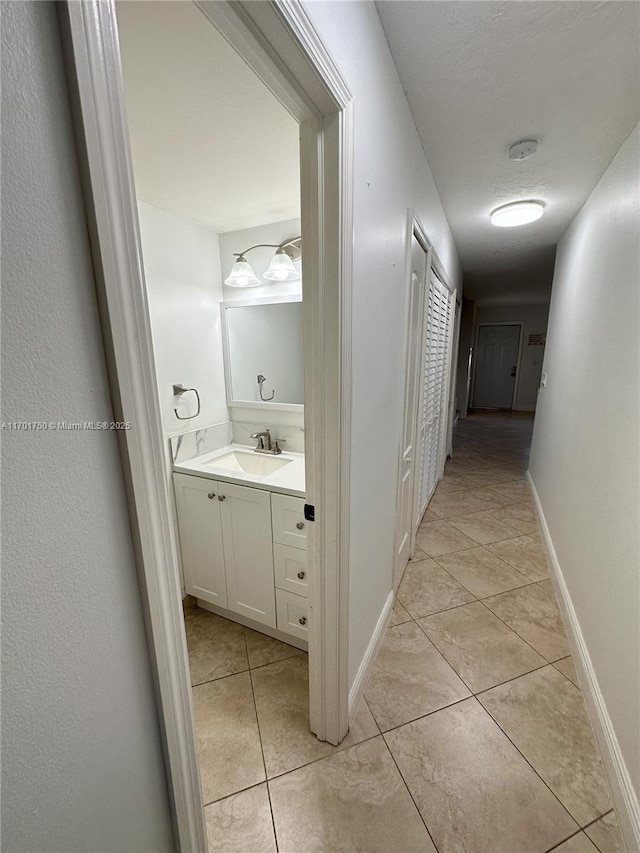 hallway featuring light tile patterned floors and sink