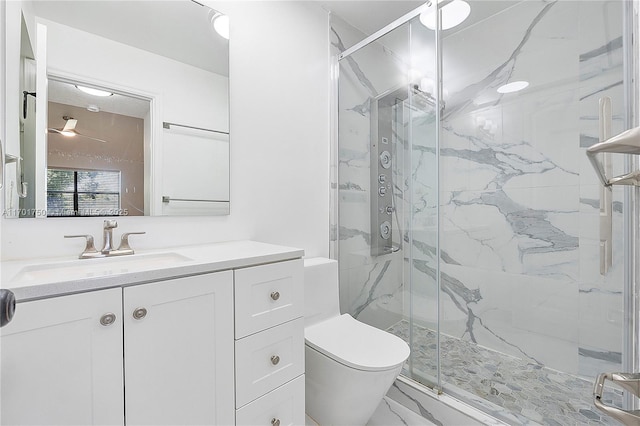 bathroom with ceiling fan, vanity, a shower with shower door, and toilet