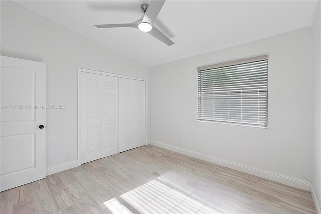 unfurnished bedroom featuring a closet, light hardwood / wood-style flooring, ceiling fan, and lofted ceiling