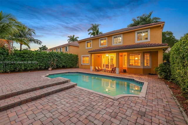 pool at dusk with a patio area