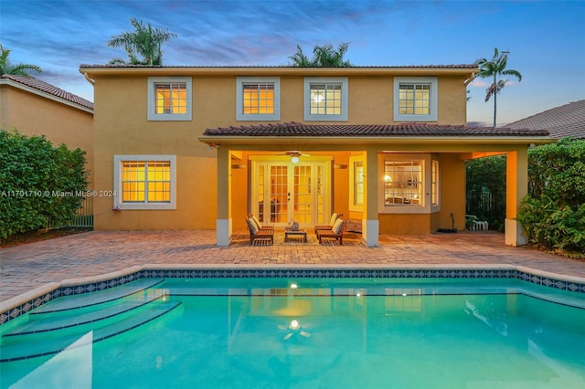 back house at dusk featuring ceiling fan, a patio area, and french doors