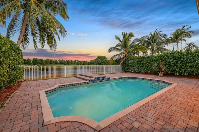 pool at dusk with a patio area