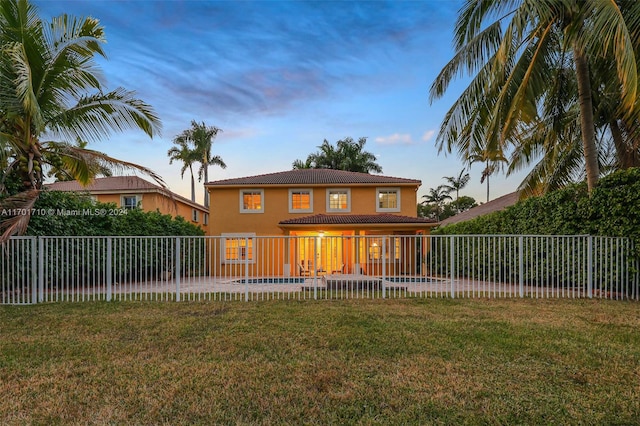 back house at dusk with a fenced in pool, a lawn, and a patio