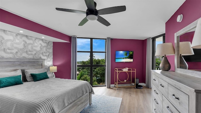 bedroom with multiple windows, ceiling fan, floor to ceiling windows, and light hardwood / wood-style flooring