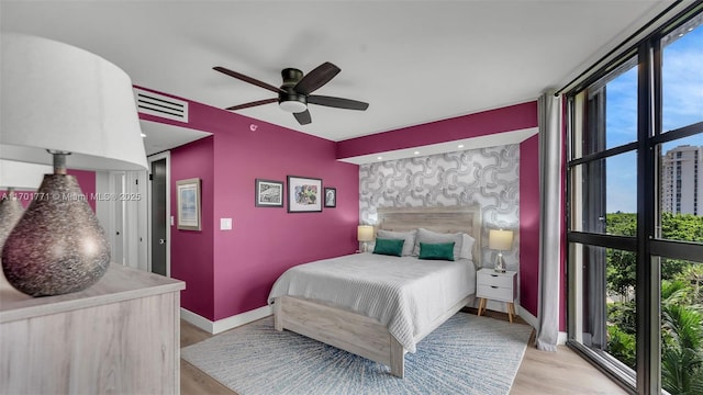 bedroom with multiple windows, light hardwood / wood-style floors, and ceiling fan