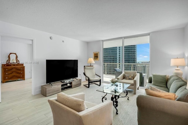 living room featuring a textured ceiling, light hardwood / wood-style floors, and floor to ceiling windows