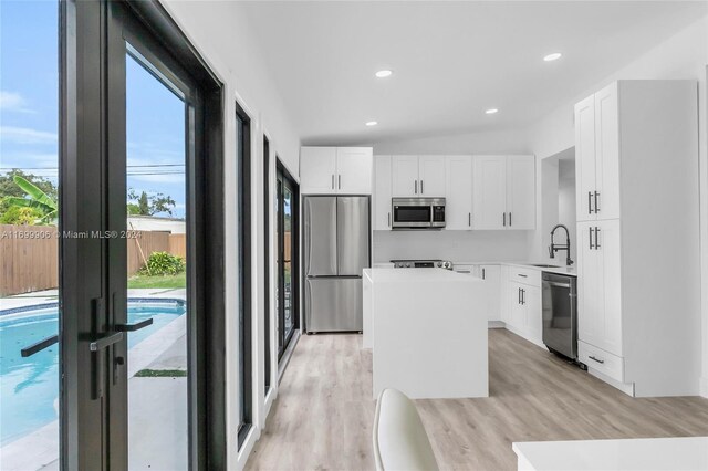 kitchen with a kitchen island, white cabinetry, and stainless steel appliances