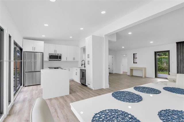 kitchen with sink, a kitchen island, light hardwood / wood-style floors, white cabinets, and appliances with stainless steel finishes