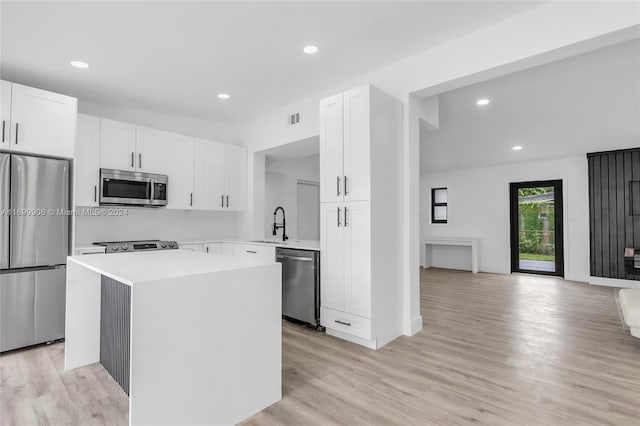 kitchen with sink, stainless steel appliances, a kitchen island, light hardwood / wood-style floors, and white cabinets