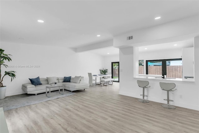 living room with sink, french doors, and light wood-type flooring