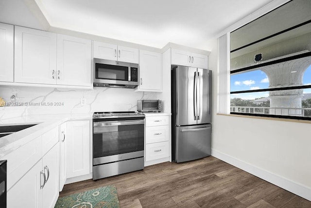 kitchen with white cabinets, dark hardwood / wood-style floors, light stone counters, and stainless steel appliances