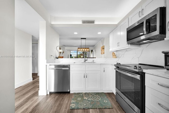 kitchen featuring kitchen peninsula, stainless steel appliances, sink, white cabinets, and dark hardwood / wood-style floors